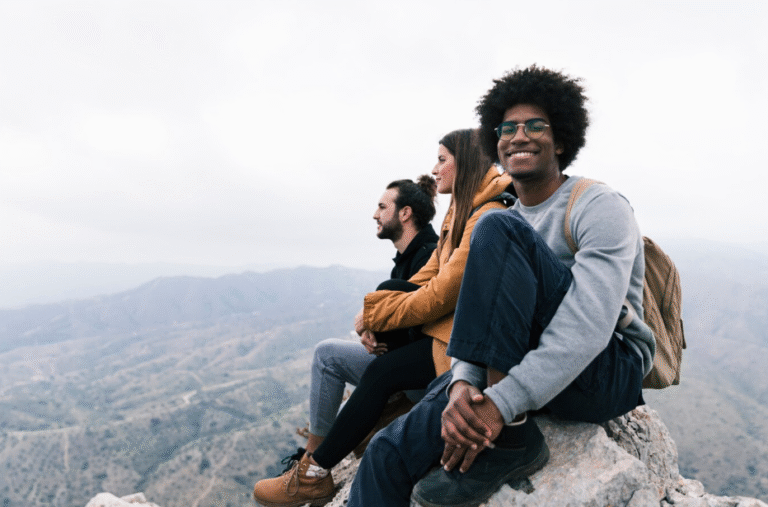 portrait-smiling-man-sitting-top-rock-enjoying-with-his-friend
